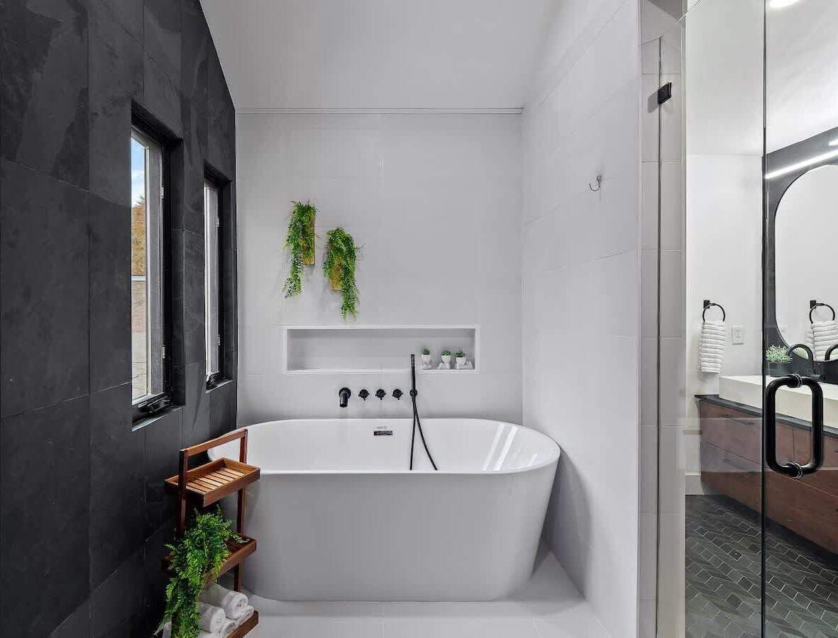 Een moderne badkamer met een vrijstaand bad, een douchecabine van glas en een minimalistisch design.