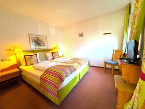 A hotel room with a bed, a desk with a computer, a chair, and a TV. - Fackler Apartments 6 Hirschberg – Bavarian Comfort with Lake View in Tegernsee (Tegernsee)