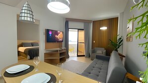 A modern living room with a dining area, a TV mounted on the wall, and a sliding door leading to a balcony. - SHB - Unparalleled view of Gonzaga Beach (Santos)