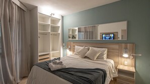 Ein Hotelzimmer mit Bett, Kleiderschrank, Spiegel und Fernseher.