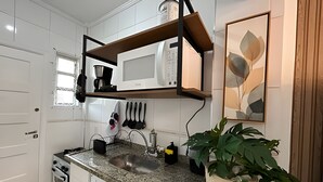 A kitchen with white cabinets, a granite countertop, a built-in microwave, and a potted plant.
