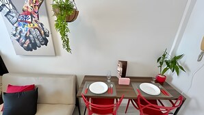 A dining area with two red chairs, a wooden table, and a white plate on each chair.
