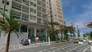 A modern building with multiple floors, a parking area, and some greenery. - SHB - Beachfront in Pitangueira, Guaruja (Guarujá)