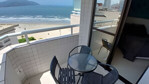 Un balcone con tavolo e sedie, vista sulla spiaggia e sull'oceano.