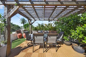 Une terrasse extérieure dotée d’une pergola, d’un espace salon et de plantes en pot.