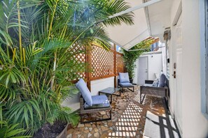 A patio with outdoor seating, a wooden lattice partition, and a potted plant. - Updated Condado Retreat Walk to Beach & Nightlife (San Juan)