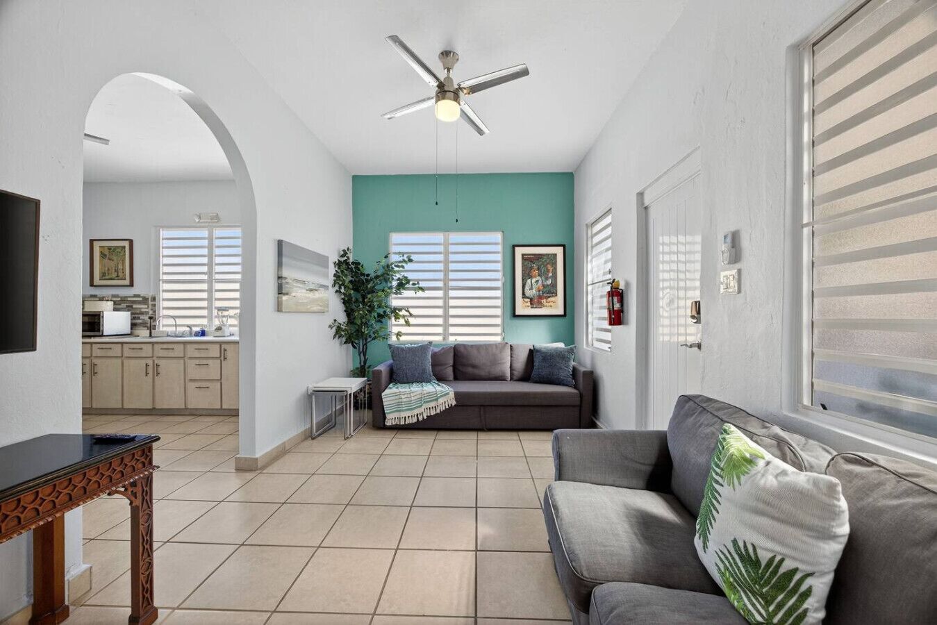 A spacious living area with a grey sofa, a wooden coffee table, and a ceiling fan.