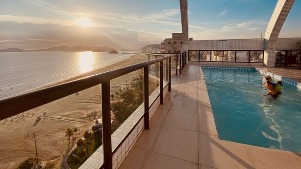 A rooftop pool with a view of the beach and ocean during sunset. - SHB - Sea Glow: Balcony with Ocean View (Santos)