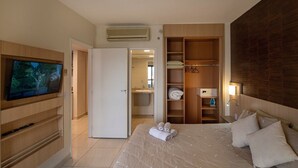Camera d'albergo con un letto, una TV, un armadio e un bagno visibile attraverso una porta aperta.