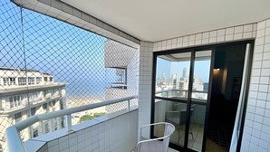 Ein Balkon mit Blick auf Gebäude, einem Stuhl und einer Glastür.