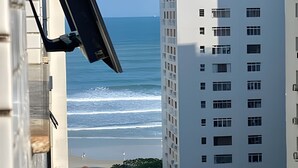 Ein Hochhaus mit zahlreichen Fenstern und Balkonen mit Blick auf einen Strand und Wellen.
