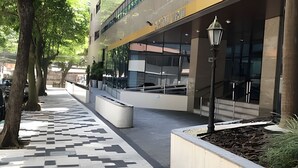Ein modernes Gebäude mit Glasfassade, einem gemusterten Gehweg und Außenbereichen mit Sitzmöglichkeiten.
