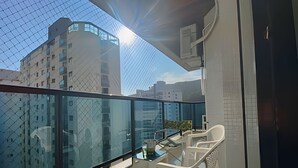 Ein Balkon mit Glasgeländer, einem Tisch und weißen Stühlen.