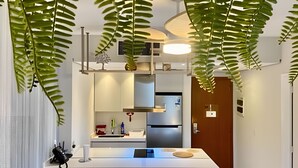 Una cocina moderna con encimera blanca, electrodomésticos de acero inoxidable y plantas colgantes.