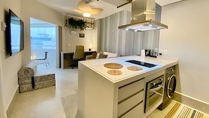 Una cocina moderna con una isla central, horno empotrado y lavadora.