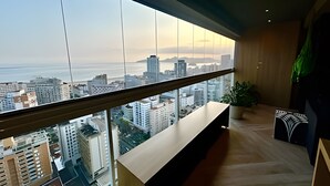 A high-rise balcony with a city view, a wooden bench, and a potted plant. - SHB - High Standard with Panoramic View! (Santos)