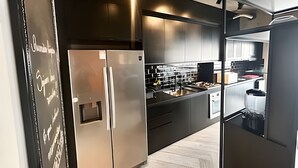 A modern kitchen with stainless steel appliances, a built-in oven, and a large island with a sink. - SHB - High Standard with Panoramic View! (Santos)