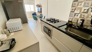 Una cocina moderna con horno empotrado, estufa a gas y un lavamanos. Se ve un comedor con una mesa y sillas al fondo.