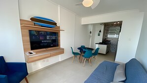 Una sala de estar moderna con un televisor de pantalla plana, un sofá azul y sillones color turquesa.