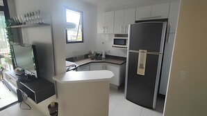 Een moderne keuken met witte kastjes, een zwarte koelkast en een magnetron.
