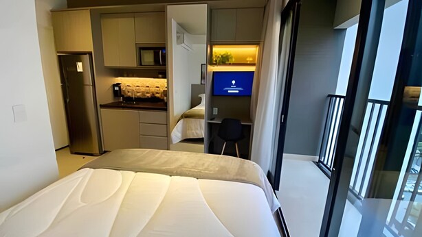 Una habitación de hotel moderna con cama, kitchenette y televisión.