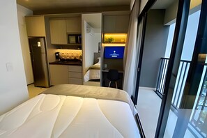 Una habitación de hotel moderna con cama, kitchenette y televisión.