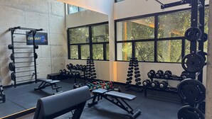 Un gimnasio con equipo de levantamiento de pesas, bancos y mancuernas.