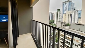 Un balcón con vista a la ciudad, un televisor y una barandilla.