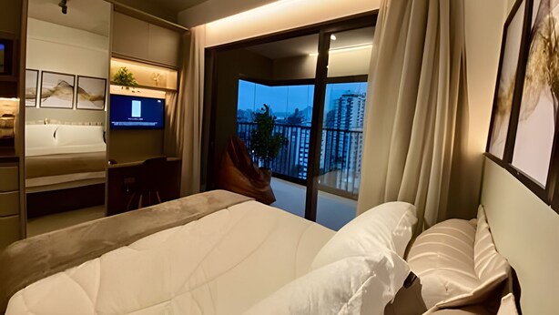 Een moderne hotelkamer met een groot bed, een televisie, een bureau en een balkon met uitzicht over de stad.