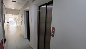 A hallway with a modern elevator and a door leading to a room. - SHB - Wake Up with the Breeze: Charming Apartment in Embaré (Santos)