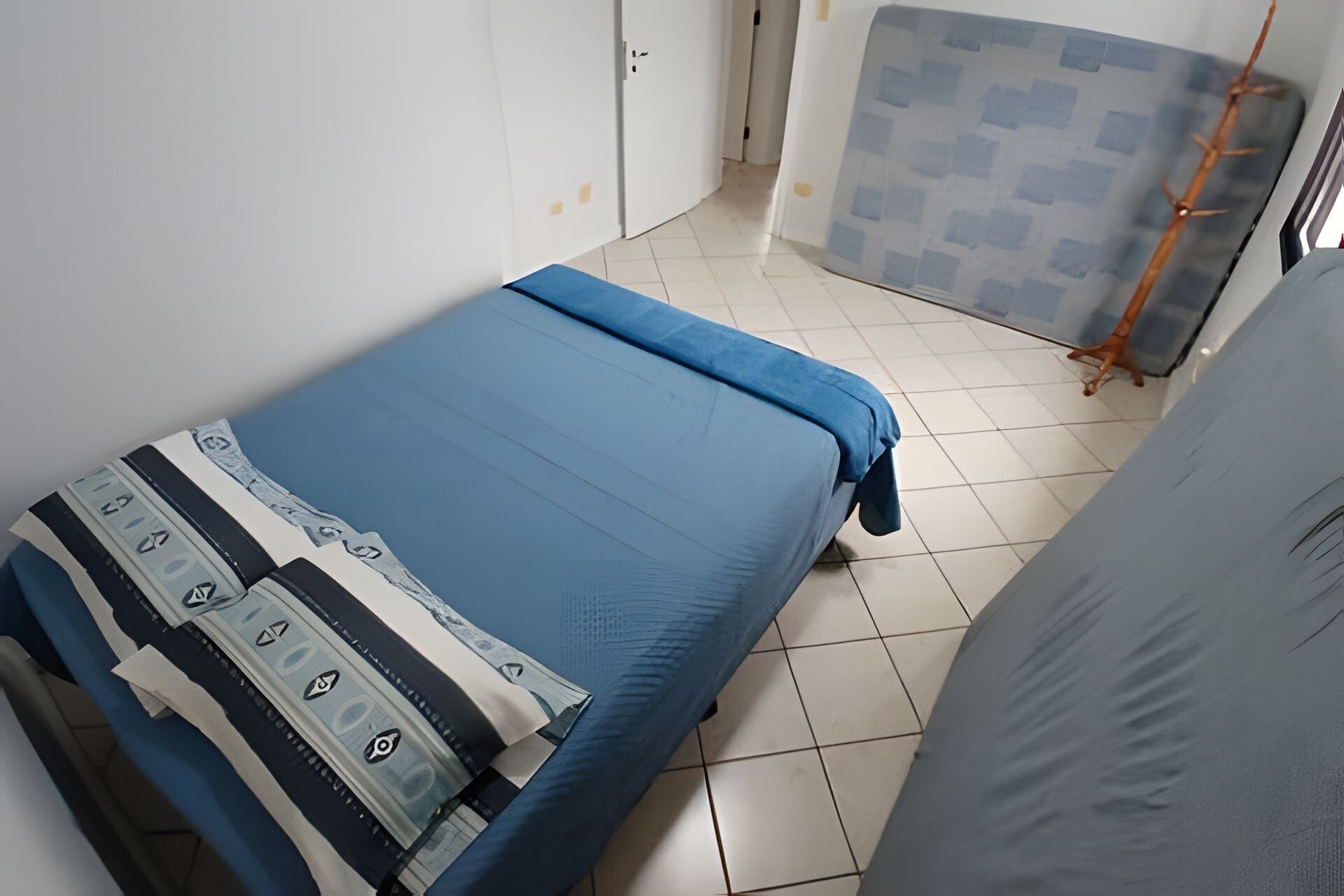 Una habitación pequeña y limpia con cama, armario y ventana con persianas.