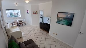 A modern living room with a sofa, a TV, and artwork on the wall. - SHB - Guarujá Private Pool and Leisure at Enseada (Guarujá)