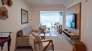 A modern living room with a sofa, chairs, a TV, and a dining area. - SHB - Style and Comfort with Gourmet Area (Guarujá)