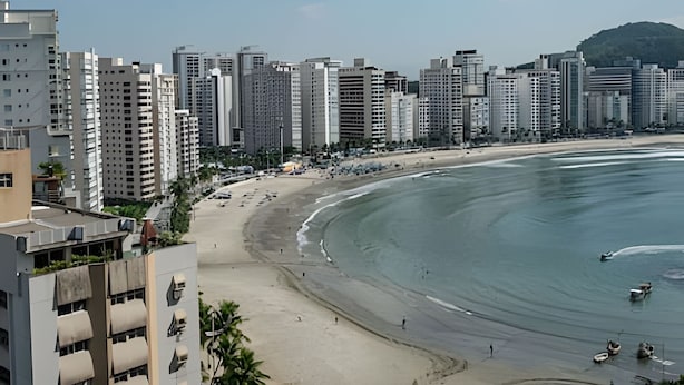 A coastal cityscape with high-rise buildings, a sandy beach, and a clear sky. - SHB - Style and Comfort with Gourmet Area (Guarujá)