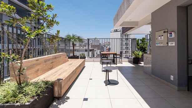A rooftop patio with a wooden bench, a small table with chairs, and potted plants. - Studio pet Friendly a 350m do Nubank Parque (São Paulo)