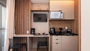 A compact kitchenette with a microwave, coffee maker, and kettle. There is a small dining area with a table and chairs. - Studio pet Friendly a 350m do Nubank Parque (São Paulo)