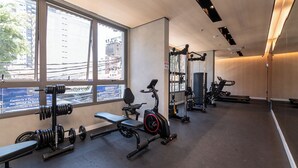 A modern gym with large windows, various exercise equipment, and a clean, spacious layout. - Studio pet Friendly a 350m do Nubank Parque (São Paulo)