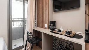 A compact hotel room with a kitchenette, a flat-screen TV, a coffee maker, and a breakfast setup on the counter. - Studio pet Friendly a 350m do Nubank Parque (São Paulo)