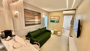 Un salon moderne avec un canapé vert, une machine à café, un comptoir en marbre et un téléviseur fixé au mur.