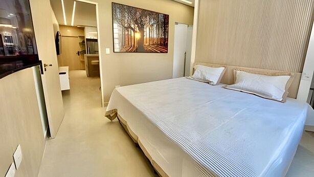 Une chambre d’hôtel moderne avec un grand lit, un tableau au mur et une tête de lit en bois.