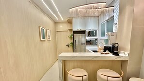 Une cuisine moderne dotée d’un îlot central, de tabourets de bar et d’un luminaire suspendu.