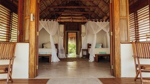 A room with two beds, each with a canopy, wooden flooring, and a thatched roof. - Rio Azul Mozambique  (Bartolomeu Dias Point)