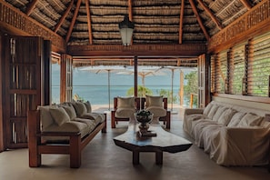 A spacious room with a thatched roof, wooden furniture, and a view of the sea. - Rio Azul Mozambique  (Bartolomeu Dias Point)