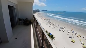 A balcony with a view of a beach, a city skyline, and a clear sky. - SHB - Facing the Sea at Pitangueiras Beach (Guarujá)