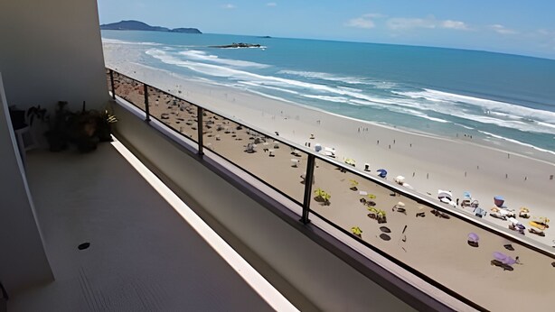 A balcony with a view of a beach, a railing, and some potted plants. - SHB - Facing the Sea at Pitangueiras Beach (Guarujá)