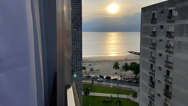 Vista de una playa al atardecer, con edificios en primer plano y un cielo despejado.