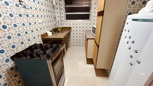 Una cocina compacta con estufa a gas, horno y refrigerador.