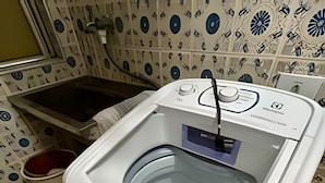 Lavadora de carga frontal con panel de control, un lavamanos blanco y baldosas estampadas en la pared.