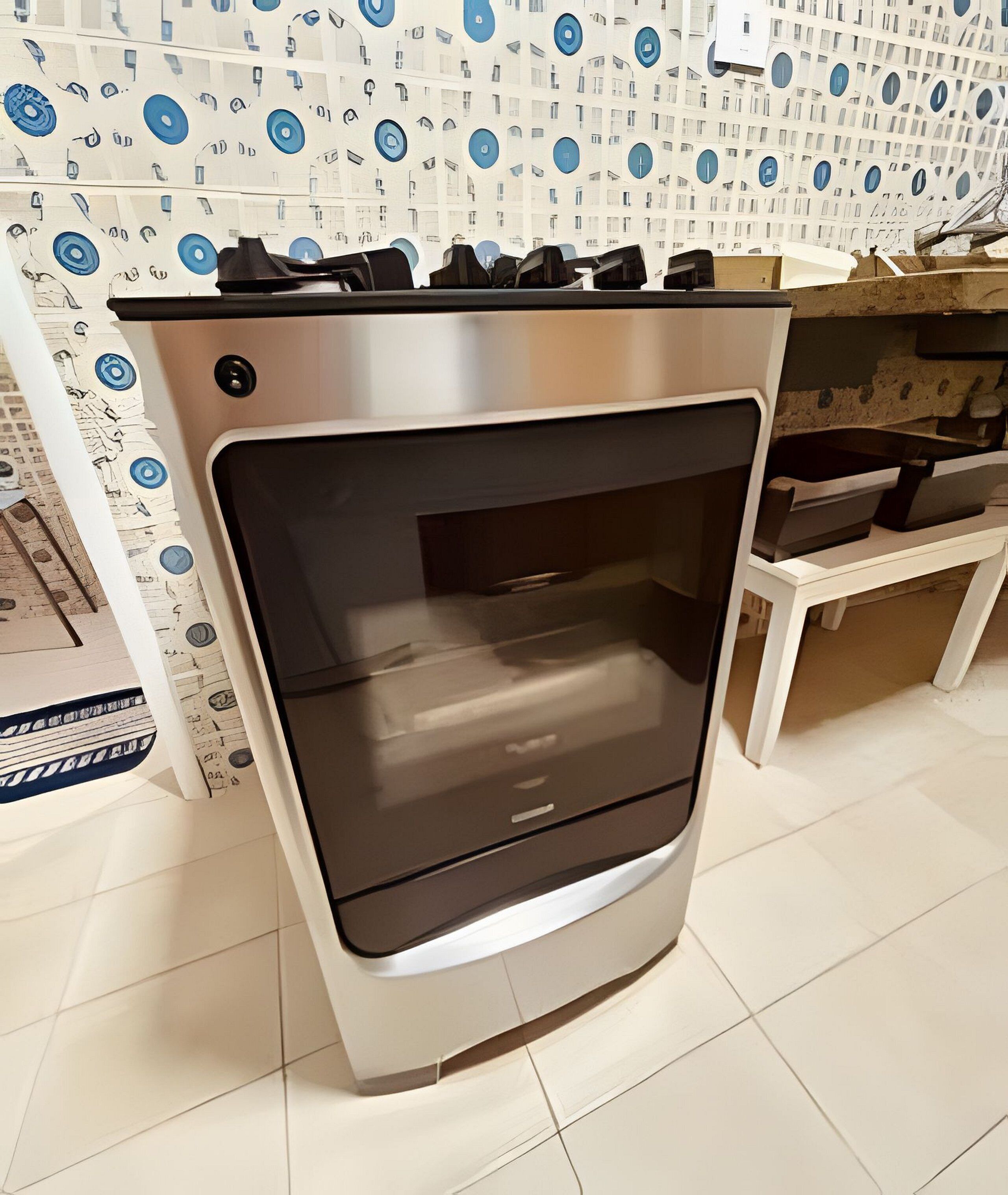 A modern kitchen with a stainless steel oven, white tiled floor, and a patterned wall.