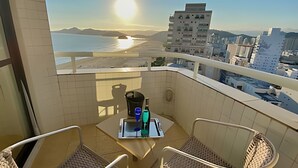 Ein Balkon mit Tisch, zwei Stühlen und Blick auf Strand und Stadtlandschaft.